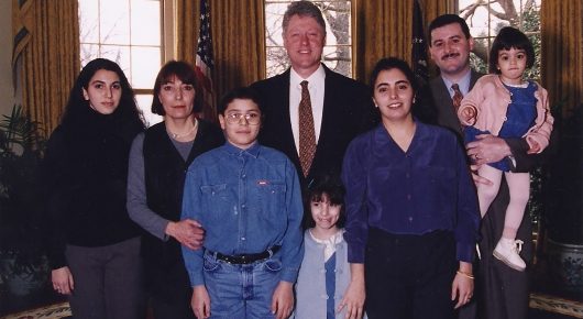Still from My Father and Qaddafi: a family group portrait, including a man in a suit and several children, posed in a wood-panelled office.