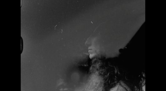 Still from My Father and Qaddafi: a faded, grainy black-and-white image of a person with dark hair in profile.
