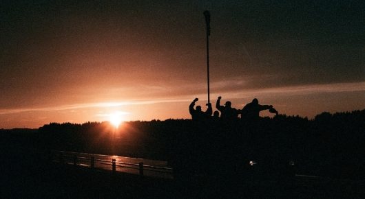 Still from The Selfish Giant: the sun sets over a dark horizon, with small silhouetted figures on the right.