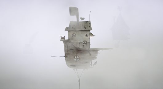 Still from Saba: the house on stilts, pale grey in thick mist.