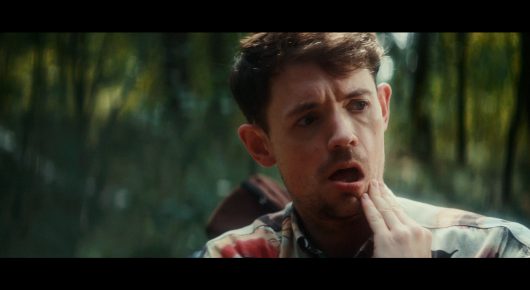 Still from Todd and The Toad: a man with a hand on his chin looks surprised, in a wood.