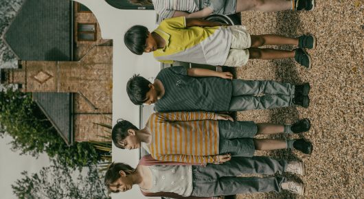 Still from Uncle Artoo: a group of children and adults stand in a row on a gravel drive in front of a house.