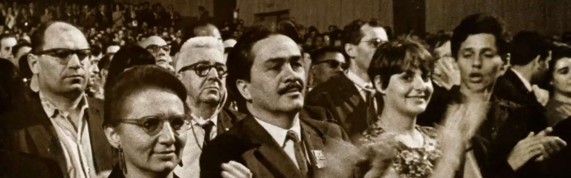 Still from Tricontinental: a black-and-white archive photograph of delegates in suits applauding in a conference hall.